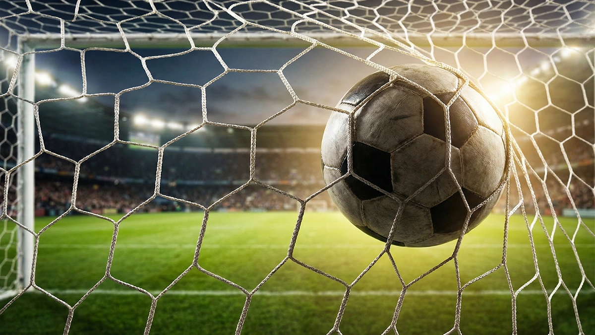 Ballon de football au fond des filets d'un but vu de l'intérieur des cages