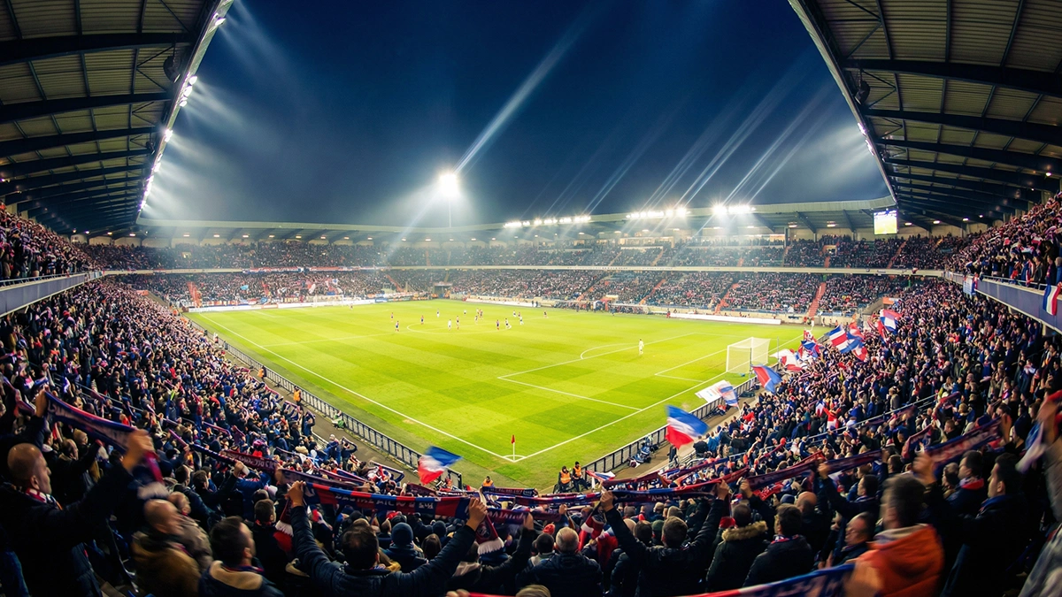 Vue panoramique d'un stade de Ligue 1 rempli de supporters lors d'un match en soirée