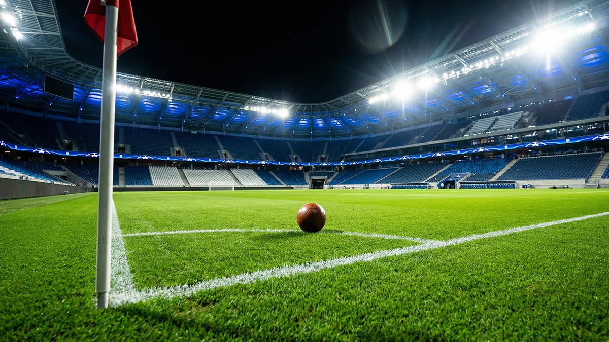 Pelouse d'un grand stade européen illuminé la nuit avant un match de Ligue des Champions