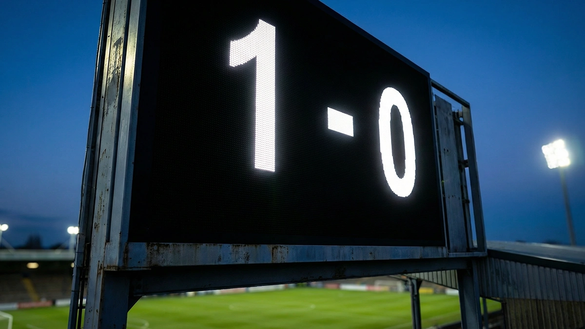 Panneau d'affichage de score dans un stade de football montrant un résultat serré