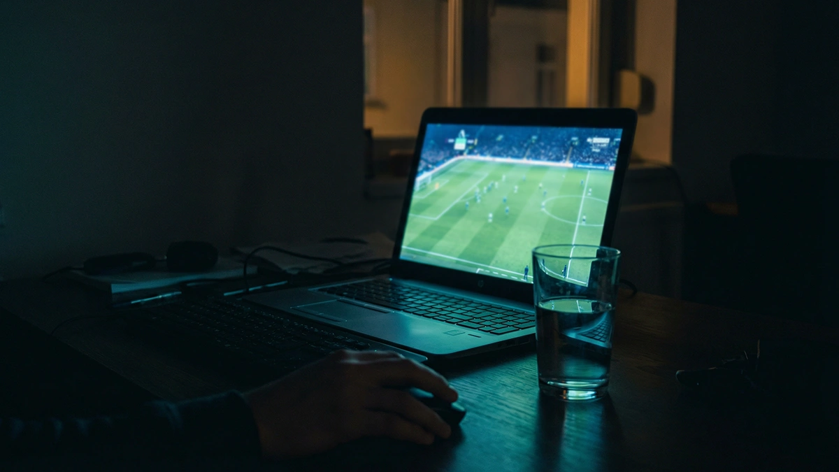 Écran de laptop affichant un match de football en streaming dans un salon le soir